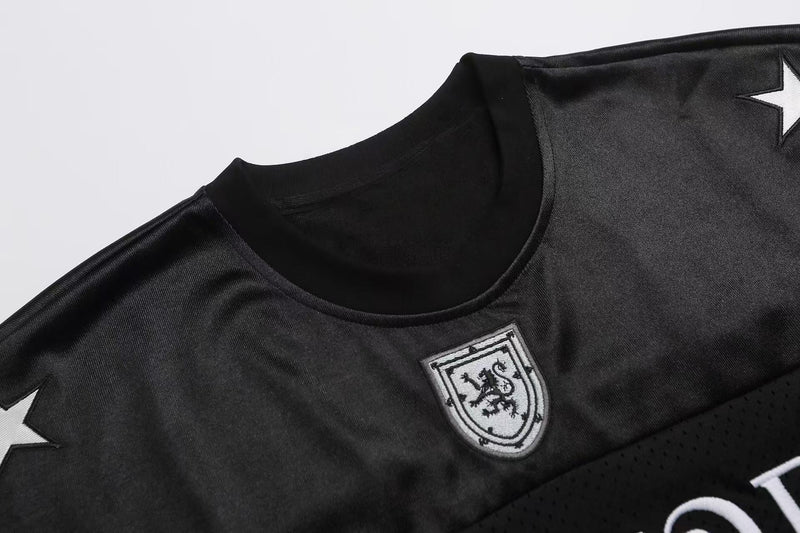 Black varsity football jersey T-shirt with shield crest, star shoulder accents, and ribbed crew neckline