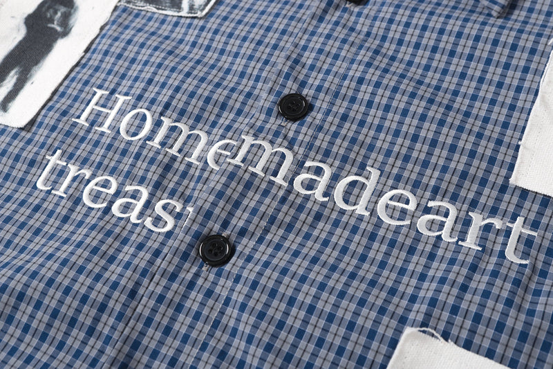 Chest detail of plaid shirt with white embroidered text and black buttons