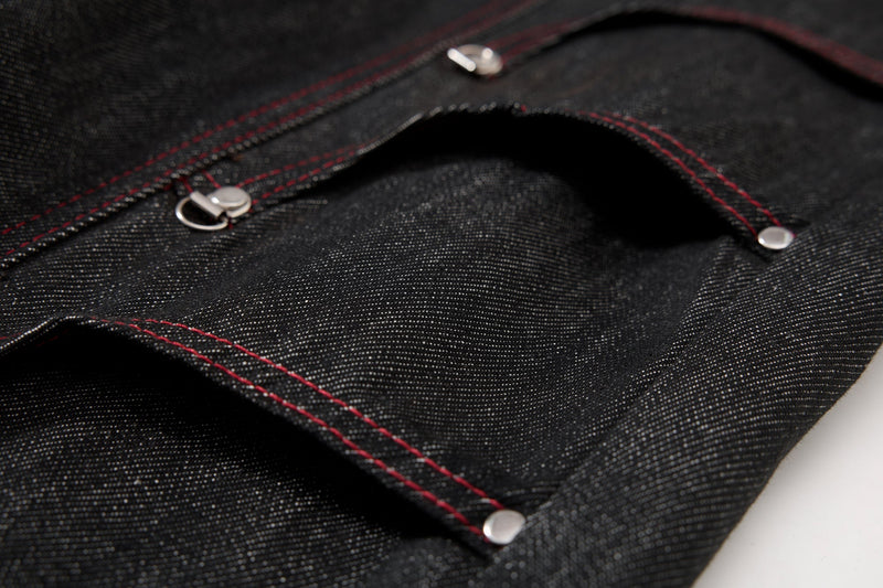 Close-up of black denim pocket opening with red topstitching and silver rivets