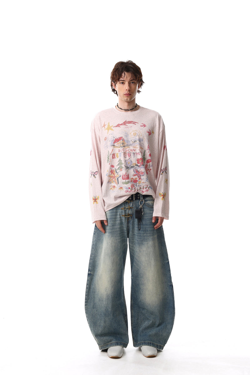Full-length model view of light pink long sleeve tee with hand-drawn graphic and wide jeans