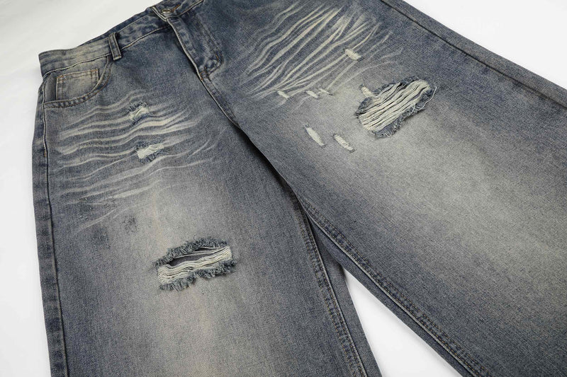 Front section of ripped wide-leg jeans with heavy fading and frayed holes