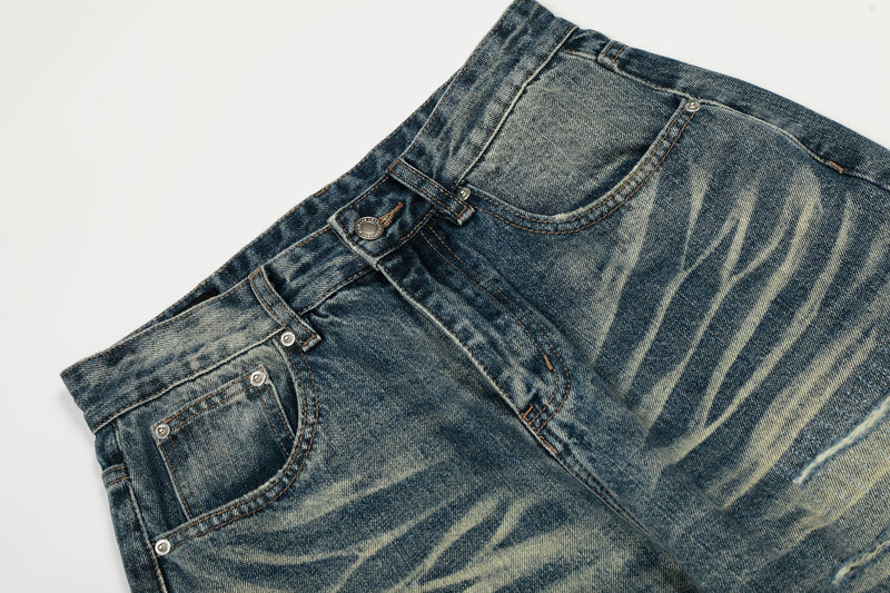 Close-up of the waistband and front pockets on washed distressed blue jeans