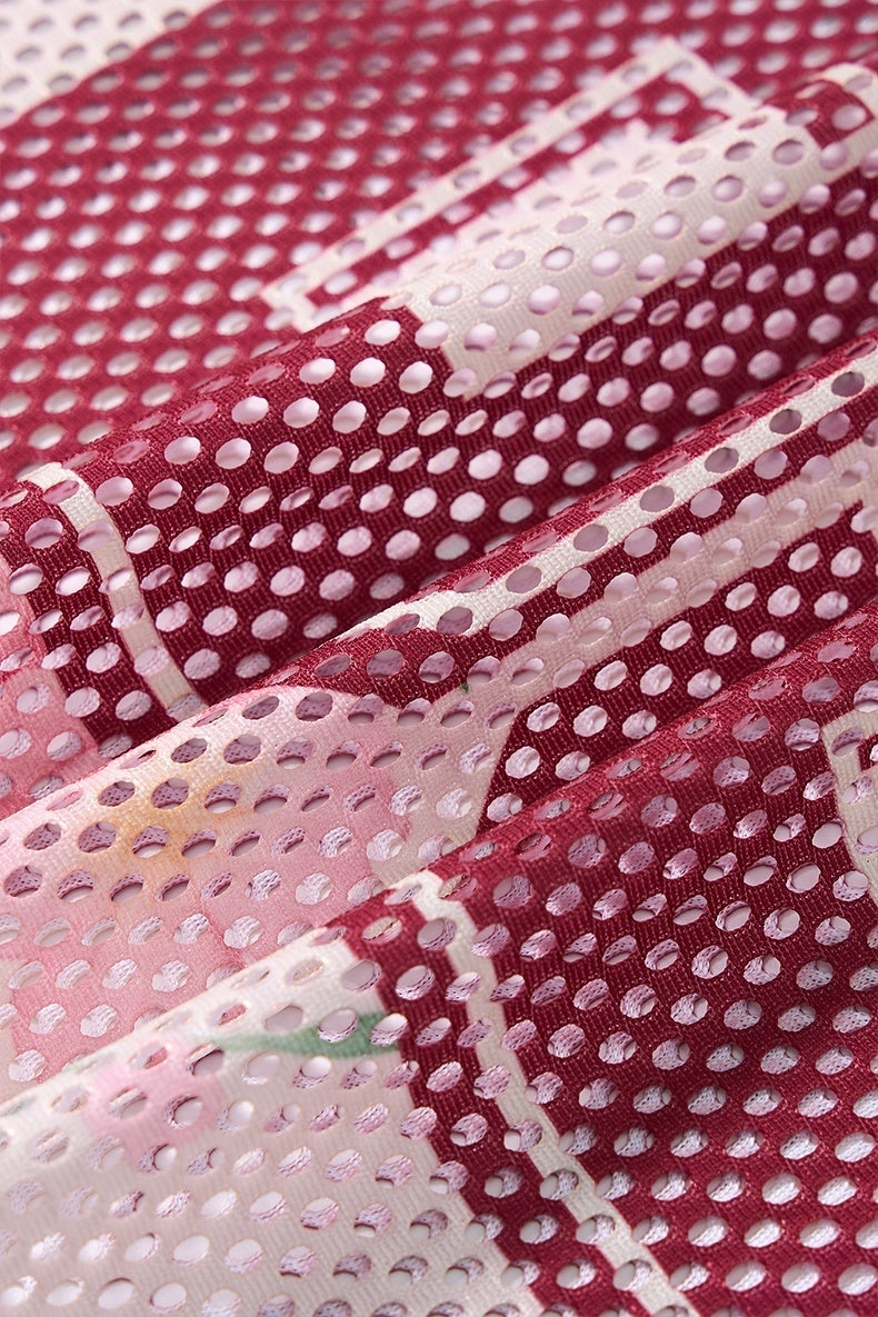Close-up of burgundy and pink floral mesh jersey fabric with perforated dot pattern and textured streetwear style