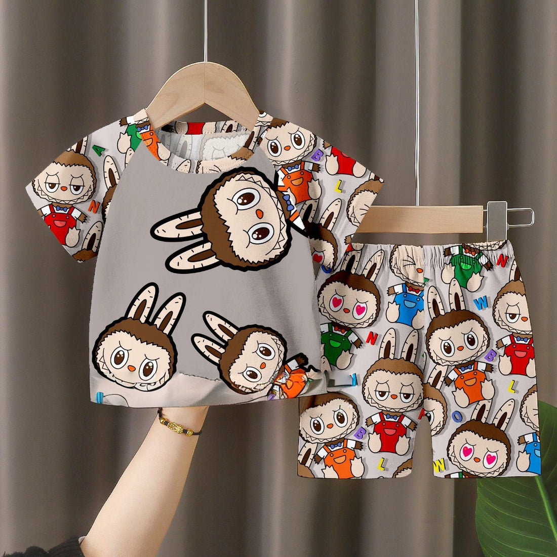 The LABUBU Baby Pajama Set features a short-sleeve shirt and shorts made from soft milk silk, showcasing colorful cartoon faces with bunny ears in red, green, and blue on a gray background.