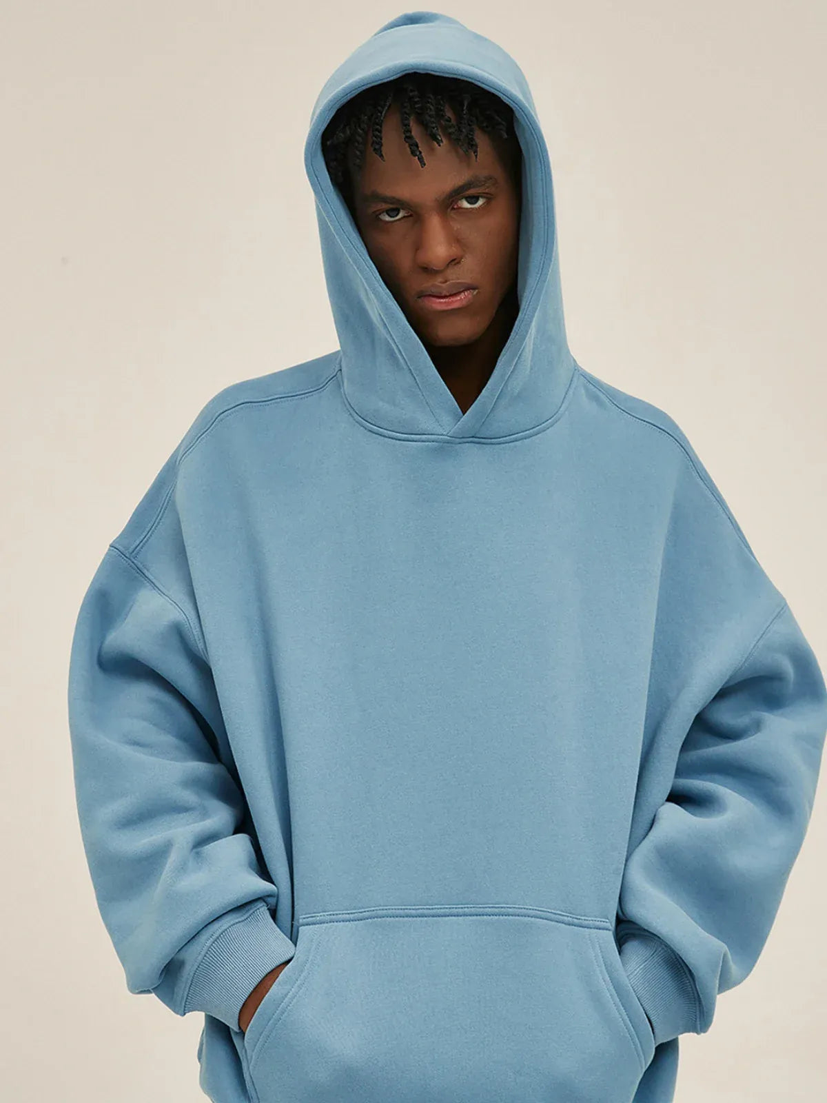 A person in a Custom Anime Character Sky Blue Hoodie - Personalized 350GSM 100% Cotton Pullover stands against a plain beige background, looking directly at the camera with the hood up.