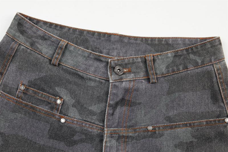 Close-up of gray camo jeans waistband with button closure, belt loops, and orange topstitching