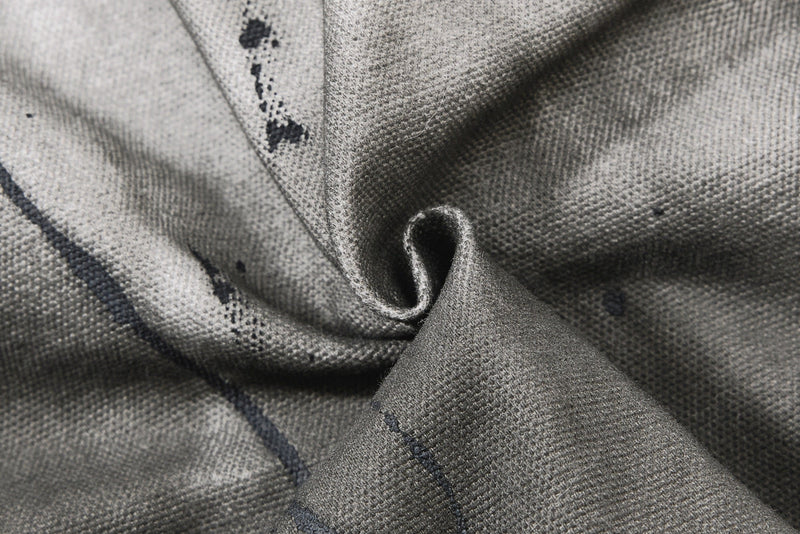 Extreme close-up of gray denim texture with stitched seam and dark wash speckles