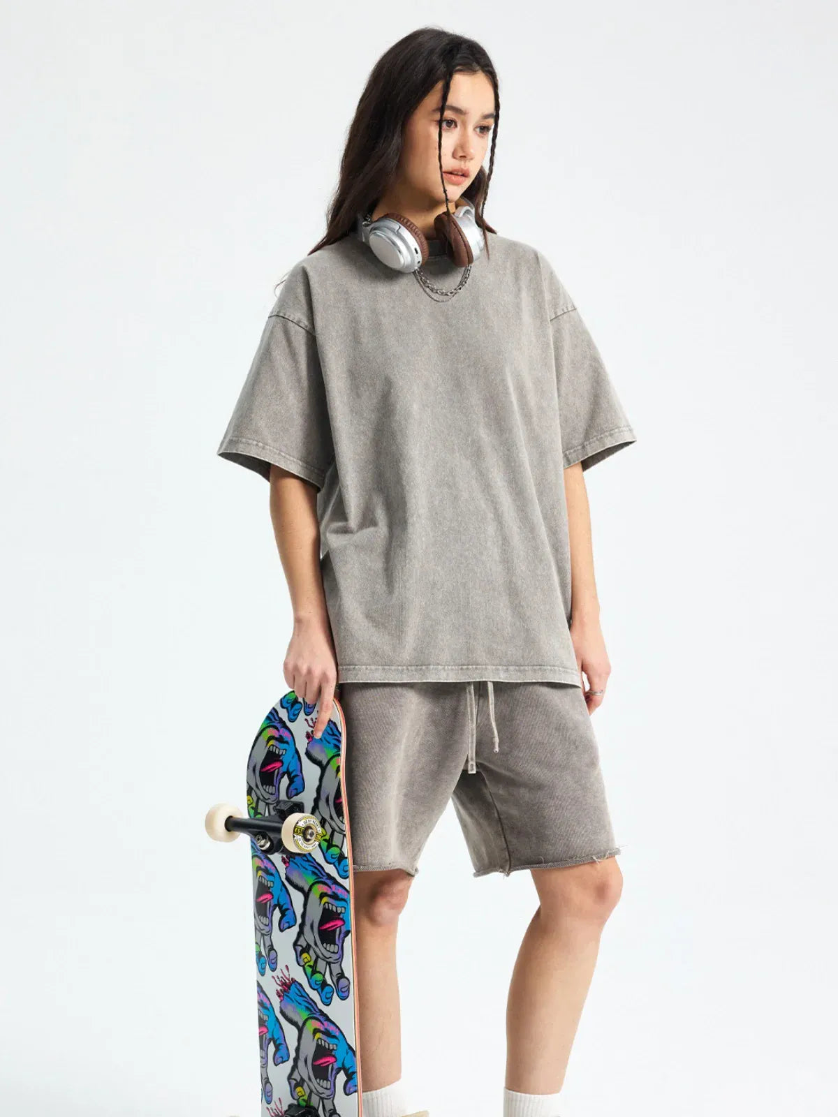 Wearing a Custom Anime Character Gray Washed T-Shirt, a person stands with a graphic skateboard and has headphones around their neck.
