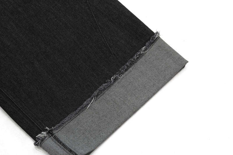 Close-up of black denim shorts cuffed hem with frayed edge and gray turn-up
