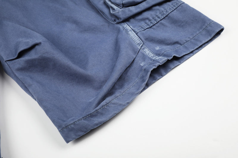 Close-up of blue cargo shorts hem and side seam with light distressing