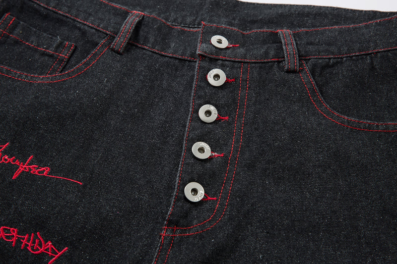Close-up of the button fly and front waist on black jeans with red stitching
