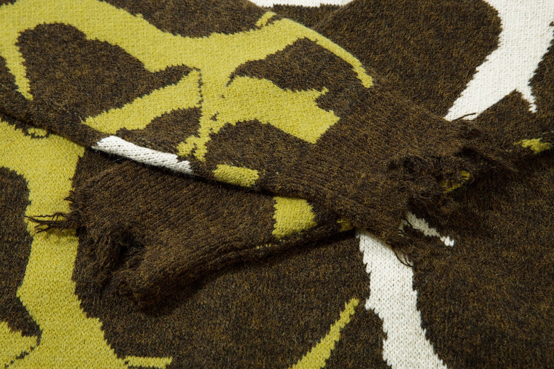 Close-up of fuzzy knit sweater sleeve seam in olive, yellow and white abstract camo