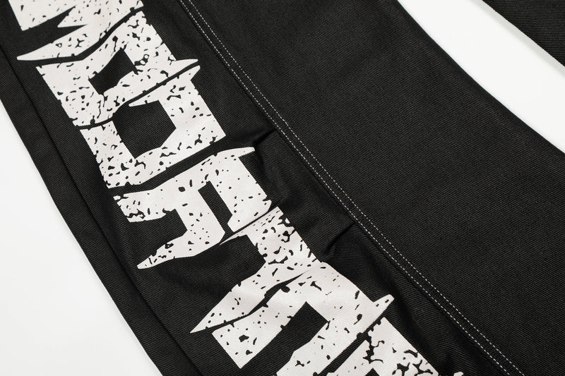 Close-up of the left leg graffiti print on black denim pants with contrast stitching