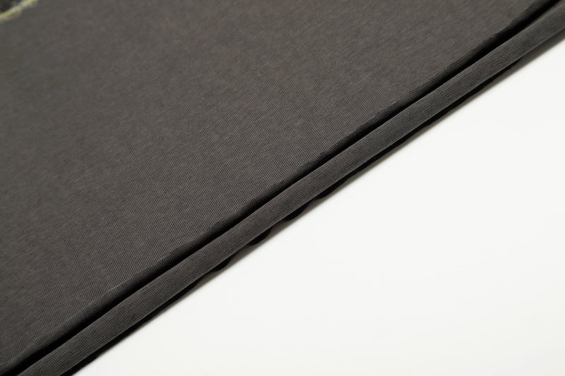 Close-up of charcoal tee sleeve and hem with clean stitched edge