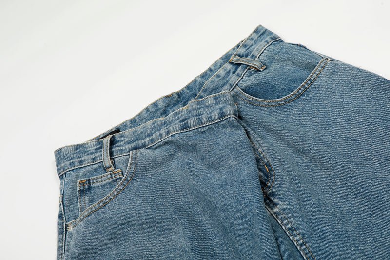 Close-up of blue denim waistband with angled front seam and belt loop
