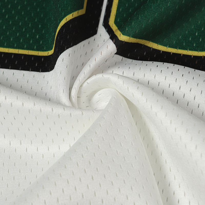 Close-up of white mesh varsity jersey fabric with green and black trim and yellow piping detail