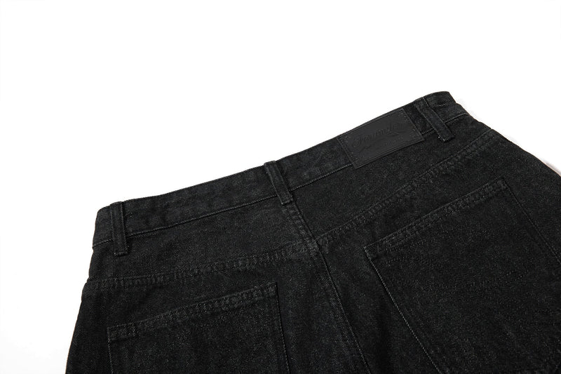 Back waistband view of black denim shorts with belt loops and logo patch
