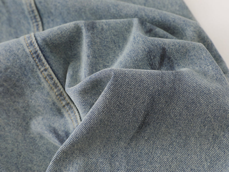 Close-up of soft faded denim fabric folds on wide-leg pants with visible twill texture