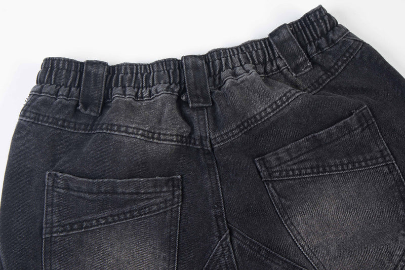 Close-up of black denim back waistband and pocket area with elastic gather and stitching