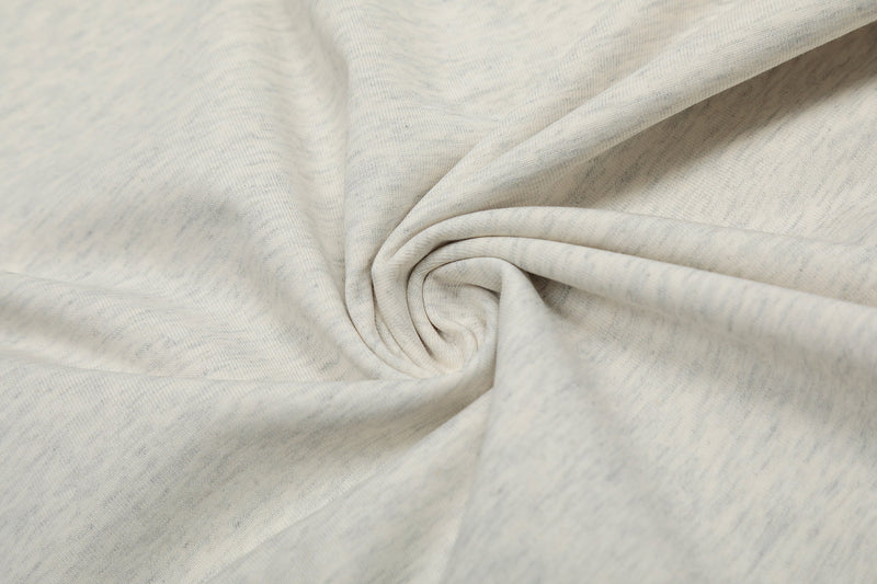 Close-up of soft cream oversized tee fabric with subtle texture and rolled folds for a relaxed streetwear look