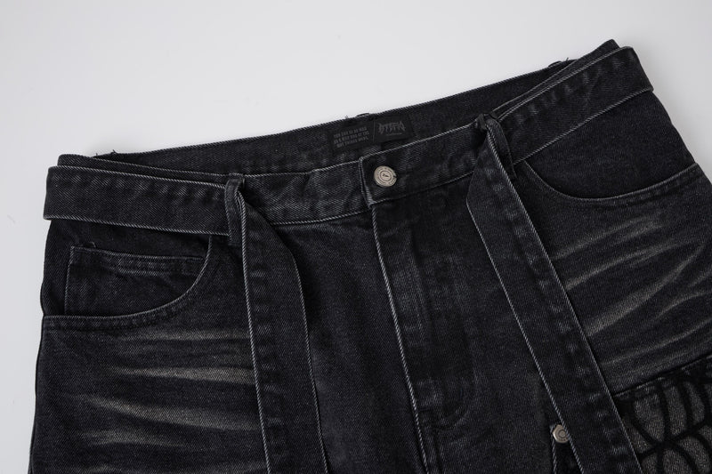 Close-up of washed black denim shorts waist with belt loops, button, and pocket edge