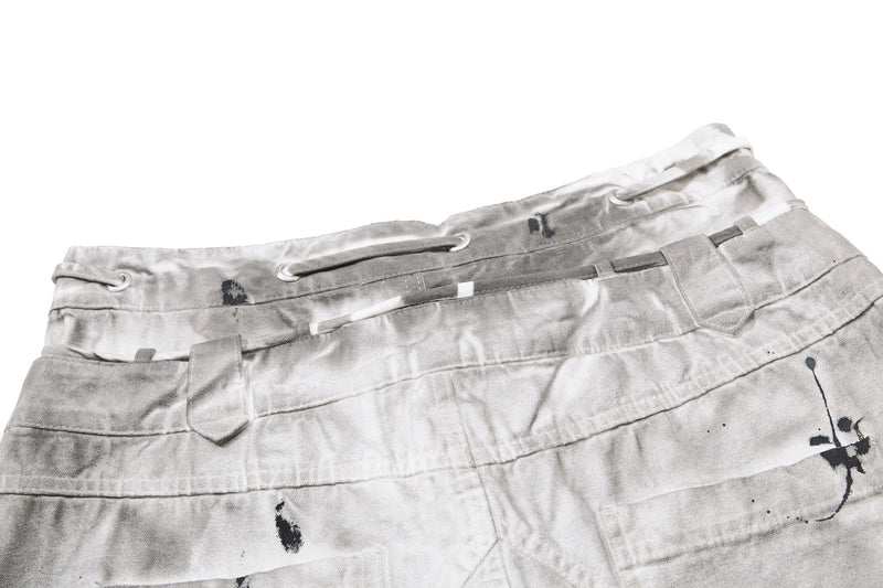 Close-up of back waistband with drawstring eyelets and splatter marks on gray denim