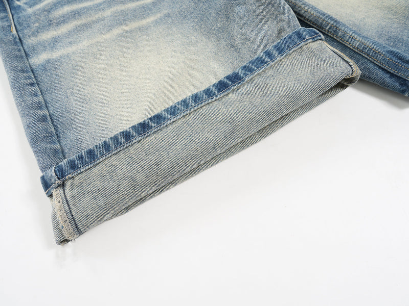 Close-up of lower hem and raw-edge detail on light wash denim shorts