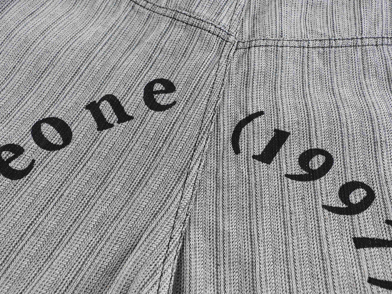 Close-up of gray pants with black printed text across the leg seams