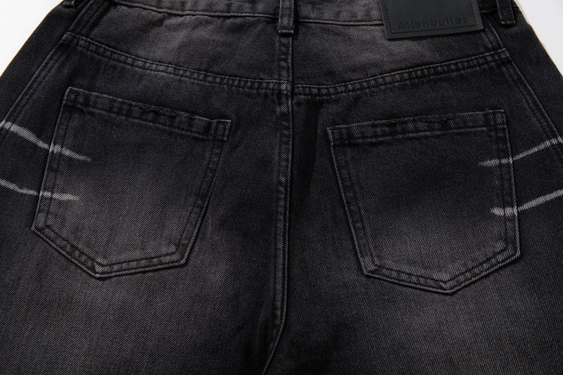 Back pocket close-up on washed black jeans with faded scratch marks and stitched pocket edges