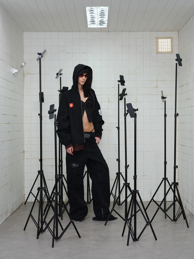 Model wearing black zip hoodie open at the front, showing plaid lining and cropped top