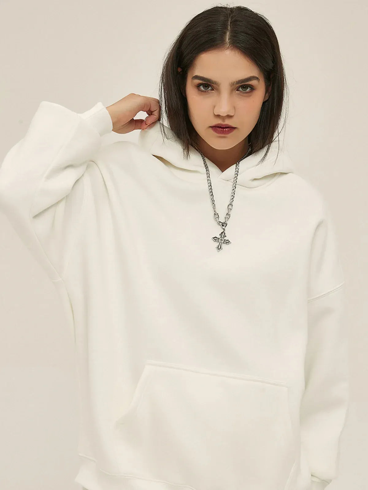A woman wearing a Custom Anime Character White Hoodie - Personalized 350GSM 100% Cotton Pullover with a front pocket and a silver cross pendant necklace, standing against a plain background.
