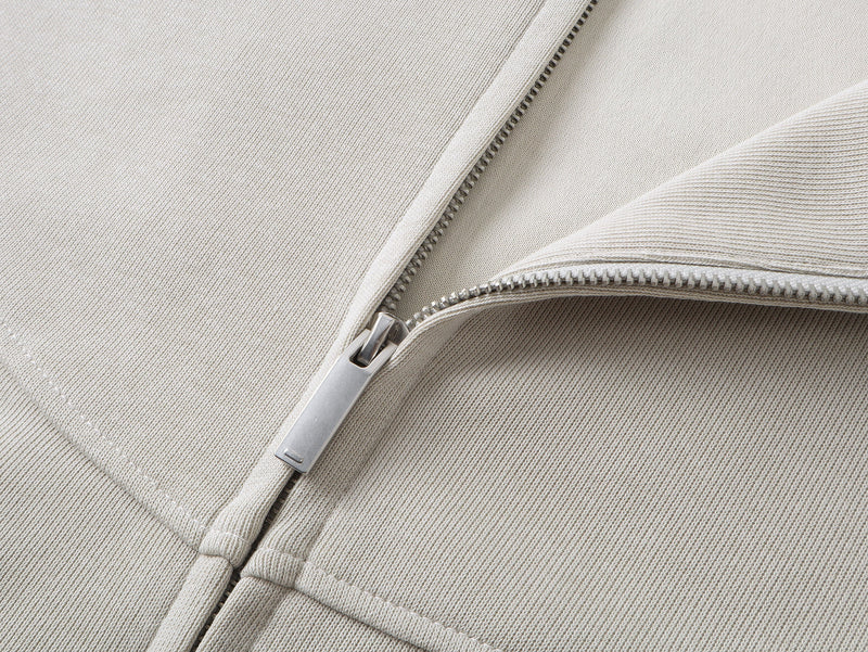 Close-up of beige hoodie zipper and front panel with textured knit fabric