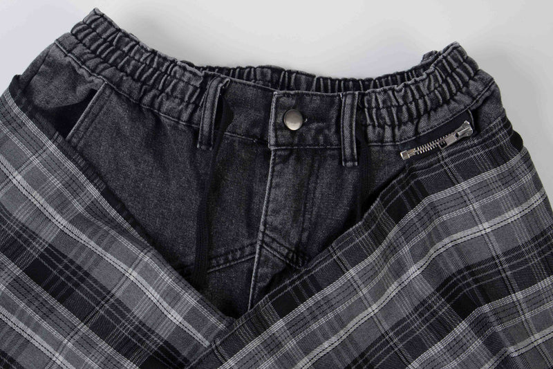Close-up of black layered plaid jeans waistband with button, zipper, and gathered elastic trim