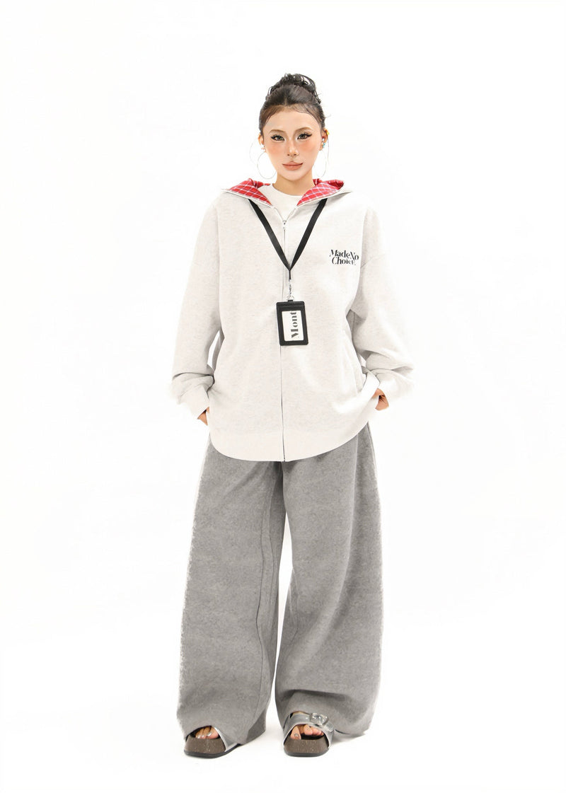 Full-length view of a model wearing a light gray zip-up hoodie with red plaid lining and gray wide-leg pants
