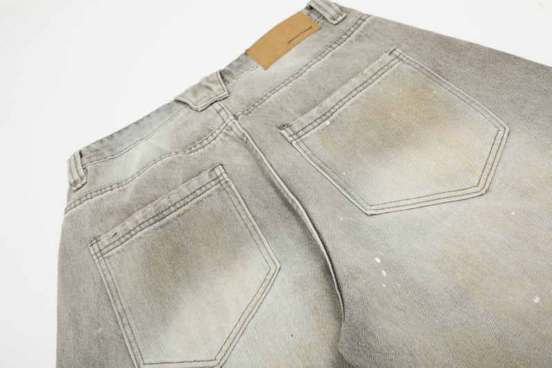 Back pocket close-up on faded gray jeans with tan label at the waistband