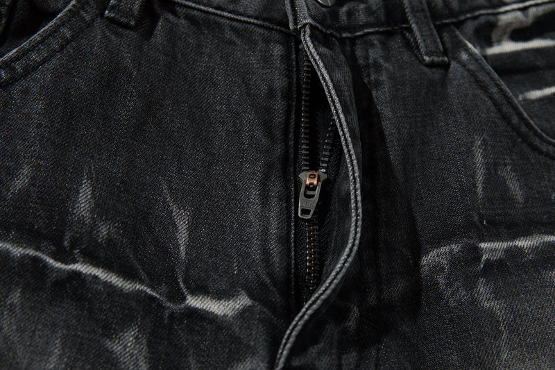 Close-up of the front zipper fly on black denim jeans with cracked wash