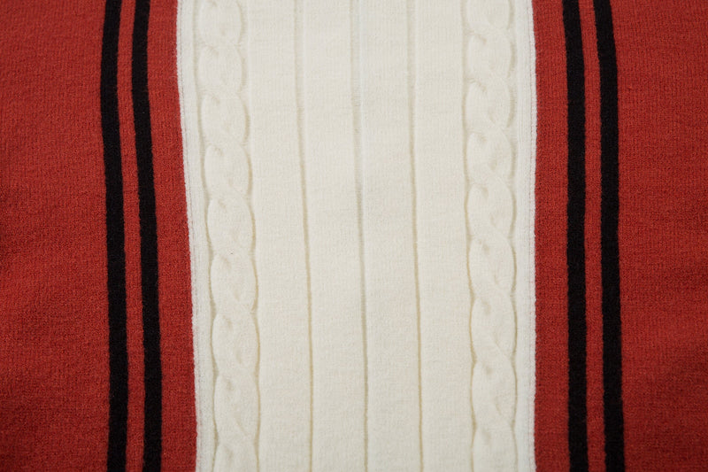 Close-up of cream cable-knit center panel framed by red sleeves and black stripes