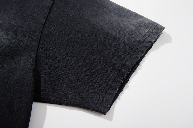 Washed black graphic tee sleeve with raw hem and faded vintage texture on dark cotton fabric