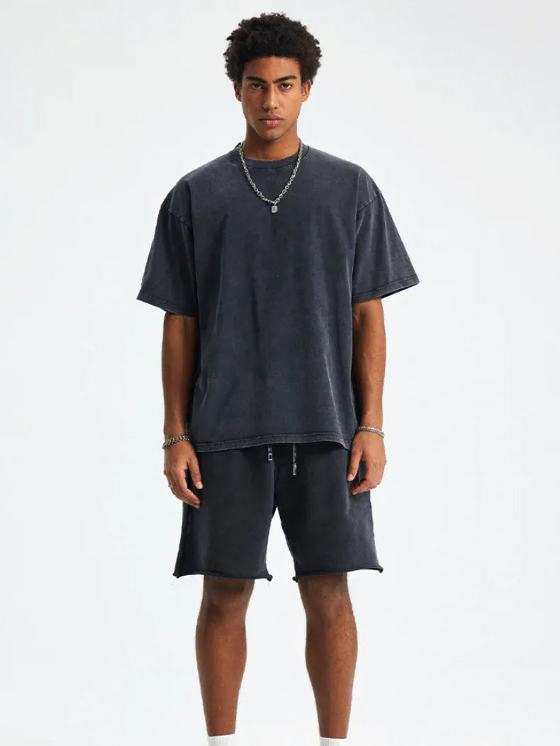A person stands against a plain background wearing a Custom Anime Character Black Washed T-Shirt - Personalized Anime Style Tee, matching shorts, and silver jewelry.