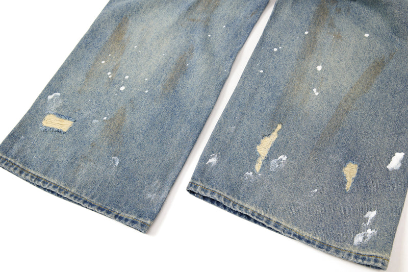 Close-up of lower legs on wide-leg jeans with ripped and paint-splatter details