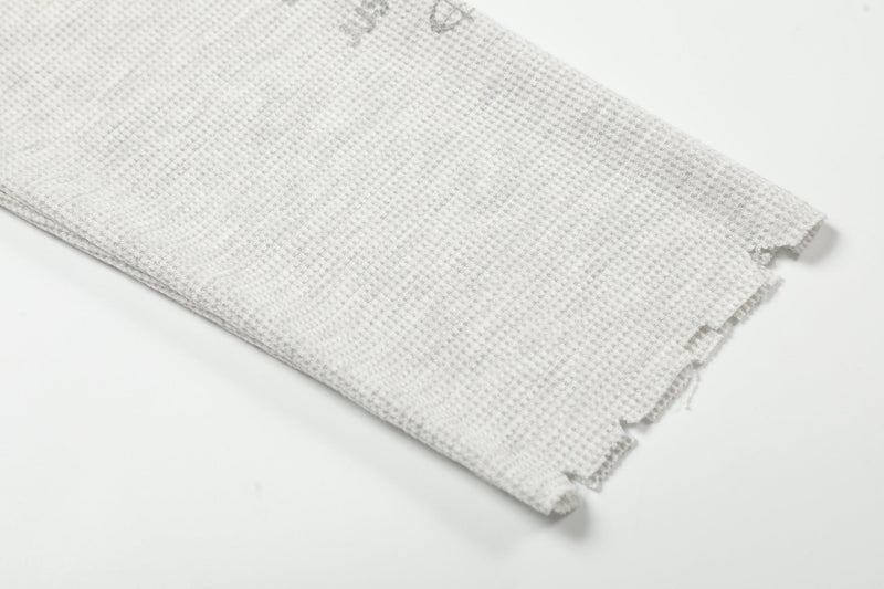 Close-up of plain light gray waffle knit sleeve with distressed cuff