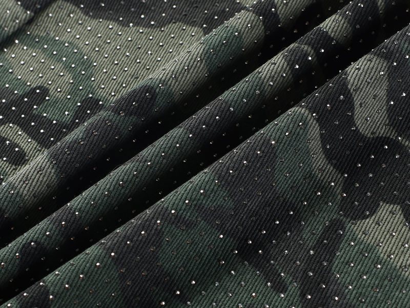 Close-up of camouflage denim fabric with scattered rhinestone details and folds