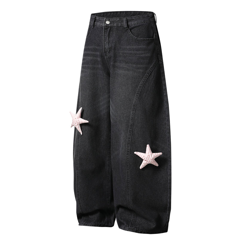 Black wide-leg jeans with pink star patches on the left leg, front view