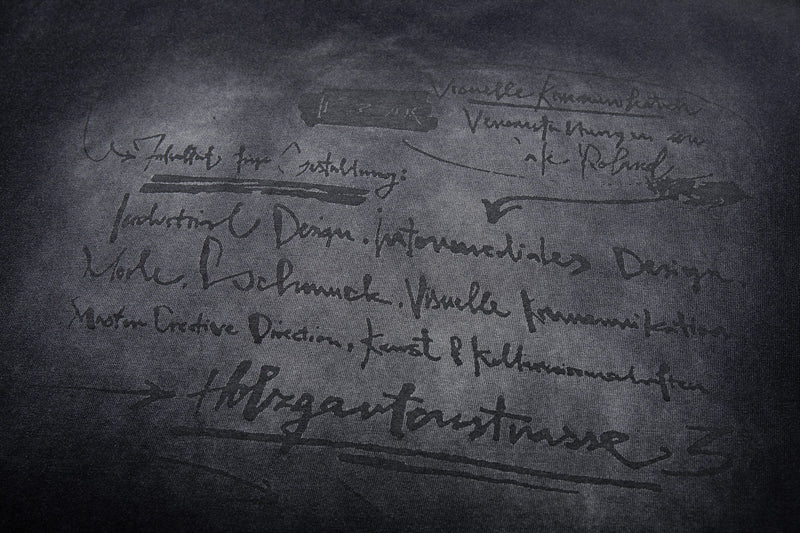 Dark washed graphic tee with handwritten-style abstract text print and vintage faded black finish