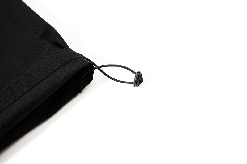Close-up of black pant leg cuff with adjustable drawcord stopper