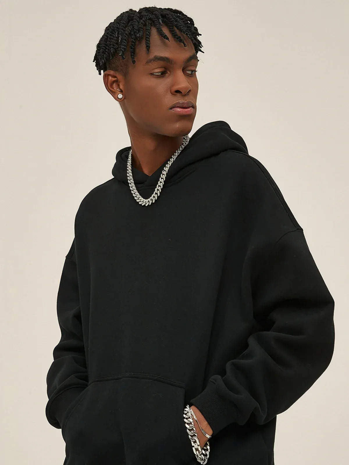Wearing the Custom Anime Character Black Hoodie - Personalized 350GSM 100% Cotton Pullover with a silver chain and earrings, a person stands with hands in pockets, glancing aside like an anime character, against a simple backdrop.
