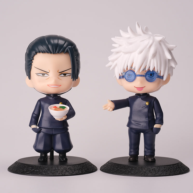 The Gojo Satoru &amp; Suguru Geto 10-piece action figure set from Jujutsu Kaisen features two chibi-style figures in dark outfits on black bases. The left one, Suguru Geto, holds a bowl of food, while the right showcases Gojo Satoru with white spiky hair and blue glasses.