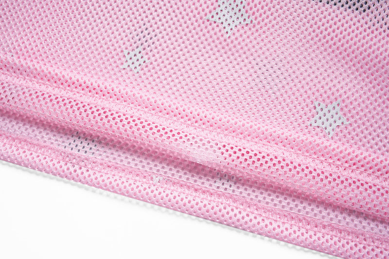 Close-up of pink mesh jersey fabric with white star print and ribbed hem detailing