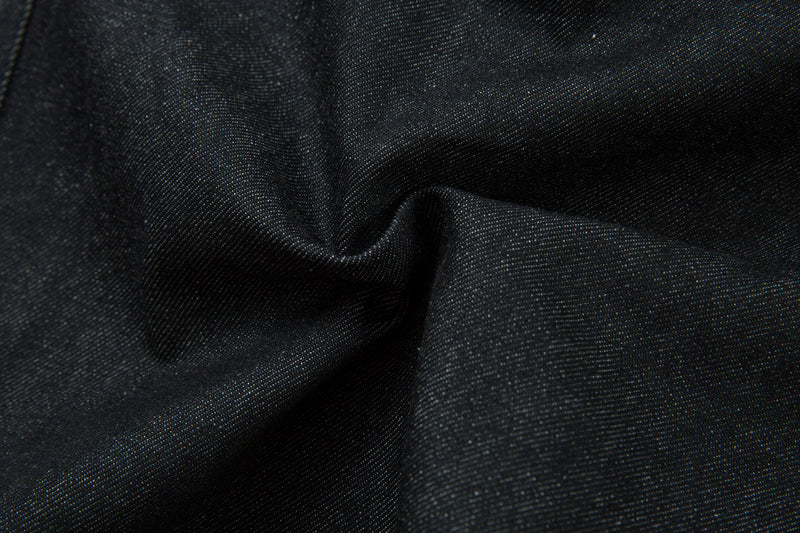 Close-up of dark denim fabric texture with soft folds and diagonal weave