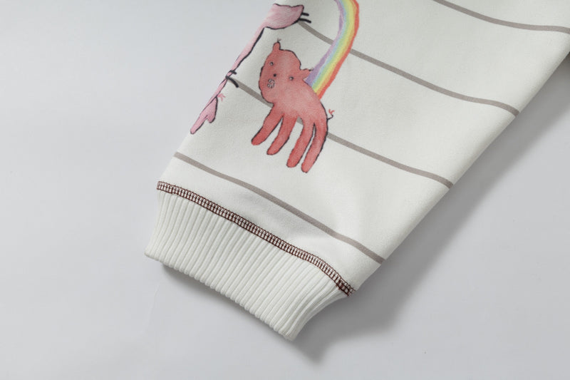 Close-up of sleeve graphic showing pink bear and rainbow on cream hoodie